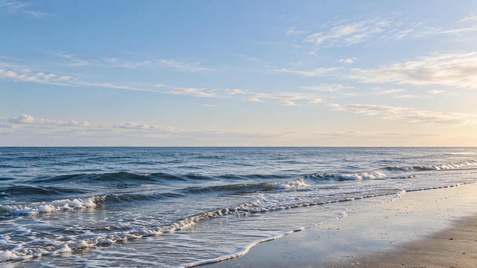 Nordseestrand mit Wellen unter hellem Himmel